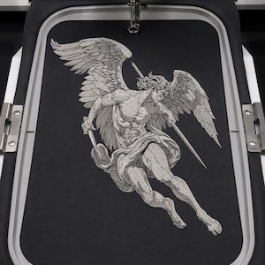 Pode incluir: Um painel de tecido preto fixado num bastidor de bordar retangular, com um bordado detalhado em fio prateado de uma figura alada em movimento, segurando um bastão ou lança longa e fina, capturado durante o processo de bordado.