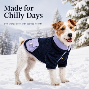 May include: A dog wearing a navy blue sherpa jacket with light purple trim and a small pocket on the side. The text on the image reads Made for Chilly Days and Soft sherpa outer with padded warmth. The dog has white and brown fur.