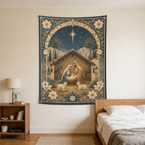 May include: A rectangular wall tapestry featuring a nativity scene with a central manger, figures in blue and brown robes, a donkey, an ox, and two lambs. The scene is framed by an ornate floral border in cream and blue against a starry night sky.