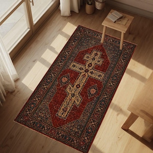 May include: A rectangular area rug featuring a deep red central field with a prominent beige and black cross motif. The rug is decorated with intricate floral and geometric patterns in shades of blue, gold, and black along the borders.