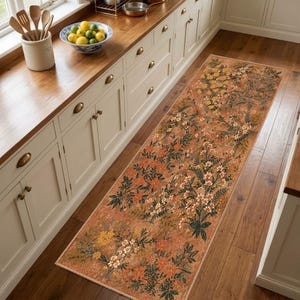 Puede incluir: Una alfombra de pasillo larga y rectangular con un fondo cálido de color terracota, adornada con un patrón denso y repetitivo de ilustraciones botánicas, que incluye pequeñas flores amarillas, blancas y naranjas con follaje verde y hojas de helecho.
