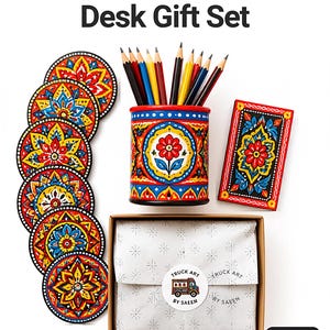 Pu&ograve; includere: Un set da scrivania in stile truck art pakistano composto da un portamatite cilindrico pieno di matite colorate, cinque sottobicchieri circolari e un vassoio rettangolare, tutti decorati con vivaci motivi floreali rossi, gialli e blu.