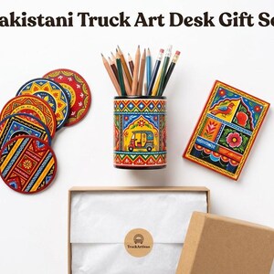 Pu&ograve; includere: Un set regalo da scrivania Pakistani Truck Art composto da un portamatite cilindrico con matite colorate, quattro sottobicchieri circolari e un blocco note rettangolare, tutti decorati con vivaci motivi geometrici e floreali.
