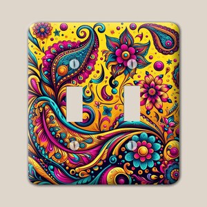May include: A double light switch wall plate featuring a vibrant, multi-colored paisley and floral pattern on a bright yellow background. The design includes intricate swirls, teardrop shapes, and stylized blossoms in shades of pink, blue, and orange.