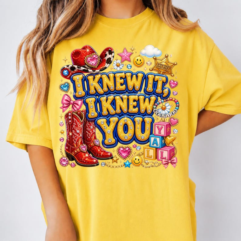 May include: A mustard yellow t-shirt featuring a graphic print with the text I KNEW IT, I KNEW YOU. The design includes red cowboy boots, a red cowboy hat, a sheriff badge, pink bows, smiley faces, hearts, and colorful alphabet blocks.
