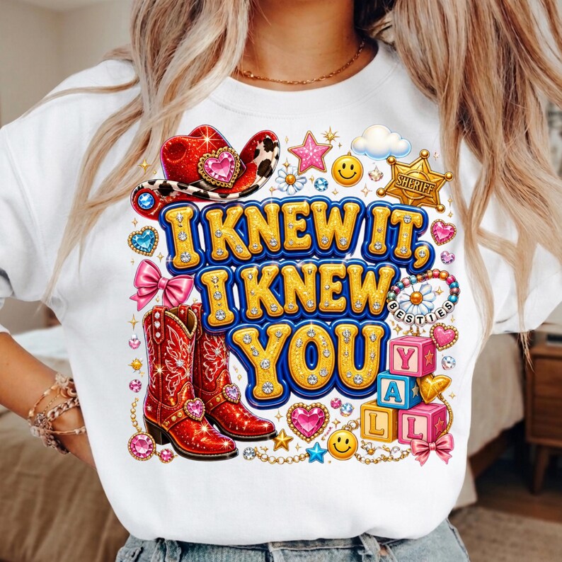 May include: A white sweatshirt featuring a graphic print with the text I KNEW IT, I KNEW YOU. The design includes red cowboy boots, a red cowboy hat, a gold sheriff badge, pink bows, smiley faces, stars, hearts, and colorful alphabet blocks.