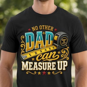 May include: Black t-shirt featuring a colourful graphic design. The design includes the text "NO OTHER DAD CAN MEASURE UP" with a measuring tape and the words "BUILT TO LAST". The text and images are in shades of blue, yellow, and gold.