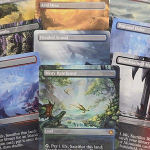 May include: A collection of Magic: The Gathering trading cards featuring full-art illustrations. Visible titles include Windswept Heath, Arid Mesa, Verdant Catacombs, Flooded Strand, Polluted Delta, Scalding Tarn, Bloodstained Mire, and Misty Rainforest.