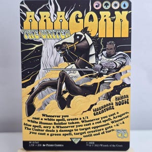 May include: A rectangular trading card titled Aragorn the Uniter, featuring a black and yellow illustration of a figure on horseback holding a sword. The card displays game text, mana symbols, and the text Legendary Creature Human Noble.