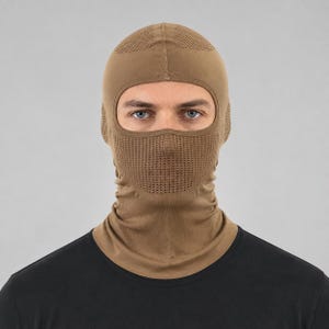 May include: A tan balaclava featuring a breathable mesh panel over the nose and mouth area, with a smooth fabric construction covering the head and neck. The design includes a single large eye opening and a seamless fit around the face and neck.
