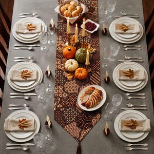 May include: A formal dining table setting featuring white plates with gold rims, linen napkins topped with wheat stalks, crystal glassware, and silverware. A patterned brown runner holds pumpkins, taper candles, and a platter of sliced turkey.