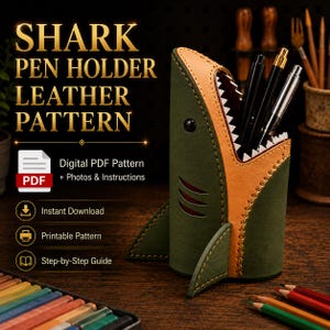 May include: A shark-shaped pen holder made of olive green and tan leather with visible stitching, featuring a wide-open mouth with white teeth holding several pens. The text SHARK PEN HOLDER LEATHER PATTERN and Digital PDF Pattern are visible.