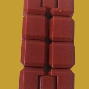 May include: A red, segmented fidget toy with a brick-like design. The toy is composed of several connected, rectangular blocks, each with a slightly beveled edge. The blocks are arranged in a vertical chain, allowing for flexible movement and manipulation.