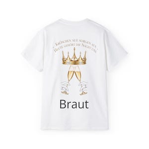 Könnte beinhalten: Ein weißes T-Shirt mit kurzen Ärmeln, das eine goldene Krone über zwei anstoßenden Sektgläsern zeigt. Der Text lautet: Krönchen auf, Sorgen aus, heute gehört die Nacht uns, und das Wort Braut ist in schwarzer Schrift unter den Gläsern gedruckt.