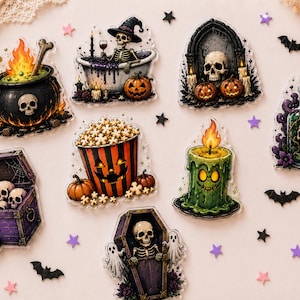 May include: A collection of Halloween-themed acrylic stickers featuring a black cauldron with fire, a skeleton in a bathtub, a skull in an archway, a potion bottle, a purple treasure chest of skulls, a popcorn bucket, a green candle, and a coffin.