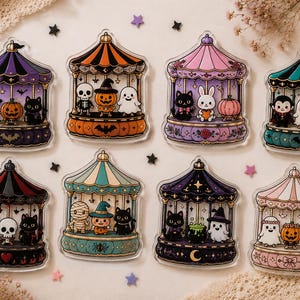May include: Eight acrylic charms featuring Halloween-themed carousel designs. Each carousel displays different characters including ghosts, pumpkins, black cats, skeletons, vampires, and mummies in various color palettes like purple, orange, and pink.