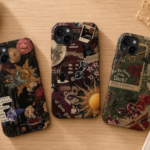 May include: Three smartphone cases featuring dark, collage-style designs. The left case shows flowers, a sun, and text. The center case displays a moon, sun, and cat graphics. The right case features tarot-inspired imagery with the text Are You Afraid of the Dark? and THE LOVERS.