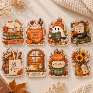 May include: A set of eight decorative acrylic stickers featuring autumn themes including a cat on books, a pumpkin spice mug, a ghost reading, a record player, a tote bag, a window scene, stacked pumpkins, and a sunflower mason jar.