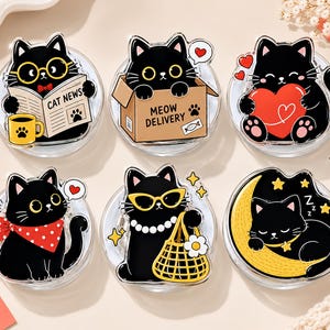 Puede incluir: Un juego de seis soportes circulares de acrílico para teléfono con ilustraciones de gatos negros. Los diseños incluyen un gato leyendo un periódico que dice CAT NEWS, un gato en una caja que dice MEOW DELIVERY, un gato con un corazón, un gato con un pañuelo rojo de lunares, un gato con gafas de sol amarillas y un bolso, y un gato durmiendo sobre una luna creciente amarilla.