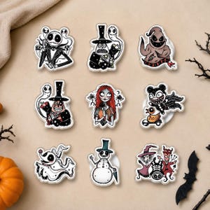 May include: A set of nine decorative pins featuring characters from The Nightmare Before Christmas, including Jack Skellington, Sally, Oogie Boogie, Zero, and other figures, each with a clear outline and detailed graphic illustrations.