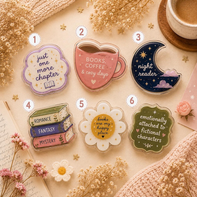 May include: Six acrylic pins with book-themed designs. Pin 1 is a purple cloud with text "just one more chapter". Pin 2 is a pink mug with "BOOKS, COFFEE & cozy days". Pin 3 is a dark blue moon with "night reader". Pin 4 shows three books labeled "ROMANCE", "FANTASY", "MYSTERY". Pin 5 is a white flower with "books are my happy place". Pin 6 is a green scalloped shape with "emotionally attached to fictional characters".