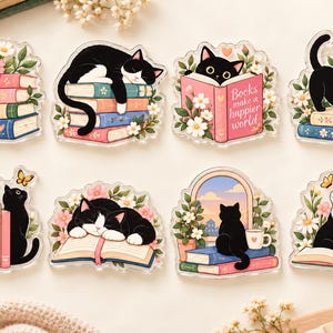 May include: A set of eight acrylic charms featuring black and tuxedo cats interacting with books, flowers, and butterflies. One charm displays the text 'Books make a happier world' and another shows 'Savor the Story'. The designs include cats sleeping on, sitting by, or reading books in various floral settings.