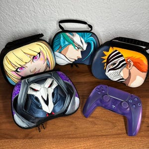Può includere: Quattro custodie rettangolari con manici e cerniere nere, ognuna caratterizzata da una diversa grafica di personaggio in stile anime sul davanti, insieme a un controller wireless per videogiochi viola con scocca traslucida e tasti neri.