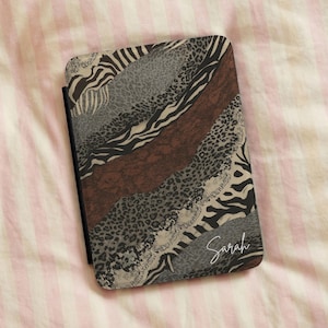 May include: A rectangular e-reader case featuring a diagonal patchwork design of various animal prints including zebra stripes and leopard spots in shades of brown, black, gray, and cream. The name Sarah is printed in white script in the corner.