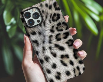 May include: A smartphone case featuring a realistic white and gray leopard print pattern with black spots. The case has a black camera cutout frame that accommodates a triple-lens camera system on the back of the mobile device.