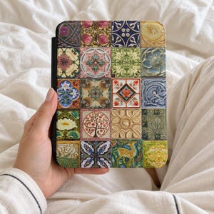 May include: A rectangular e-reader case featuring a grid of twenty square tiles, each displaying a unique, colourful illustration including floral patterns, a tree, a deer, and geometric designs in shades of green, blue, red, and gold.