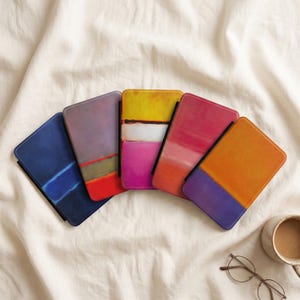 May include: Five rectangular cases with rounded corners, each featuring a unique abstract color-blocked design. The color palettes include blue, purple, red, yellow, pink, orange, and white, arranged in horizontal bands across the surfaces.