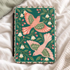 May include: A rectangular e-reader case featuring a dark green background with a repeating pattern of two pink birds in flight, surrounded by green leaves, small red berries, and white bell-shaped flowers, finished with a dotted border.