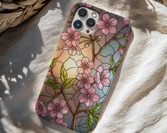 May include: A smartphone case featuring a stained glass design of pink cherry blossoms on brown branches against a soft gradient background of peach, blue, and gray. The case has a cutout for a triple-lens camera system on the upper left side.