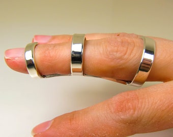 May include: A silver finger splint with three connected bands. The splint is designed to support and stabilize the finger. The bands are smooth and reflective, and the splint is worn on a finger.