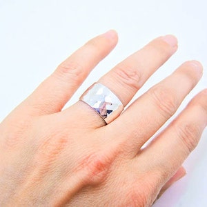 May include: A silver hammered ring with a wide band.