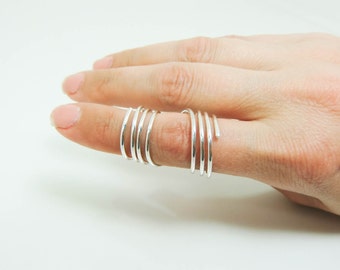 May include: A silver ring with multiple bands wrapped around each other, creating a spiral effect.