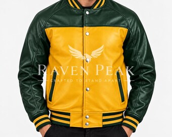 Könnte beinhalten: Eine Collegejacke mit gelbem Rumpf und dunkelgrünen Ärmeln. Die Jacke verfügt über eine Druckknopfleiste, gestreifte Rippbündchen und einen Kragen. Der Text RAVEN PEAK CRAFTED TO STAND APART ist in Weiß mittig auf die Jacke gedruckt.