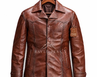 Könnte beinhalten: Eine braune Lederjacke mit spitzem Kragen, Knopfleiste und langen Ärmeln mit geknöpften Manschetten. Auf der Brust befindet sich der Schriftzug RAVEN PEAK mit Bergsymbol sowie ein Anhänger mit der Aufschrift GENUINE LEATHER.