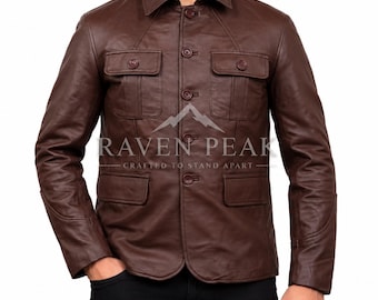 Könnte beinhalten: Eine dunkelbraune Lederjacke mit spitzem Kragen, Knopfleiste vorne, zwei Brusttaschen mit geknöpften Klappen und zwei unteren Taschen mit Klappen. Der Text RAVEN PEAK CRAFTED TO STAND APART ist auf der Brust aufgedruckt.