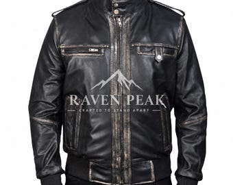 Könnte beinhalten: Eine schwarze Lederjacke mit Used-Optik, ausgestattet mit einem Stehkragen mit zwei Druckknöpfen, einem zentralen Reißverschluss, Schulterklappen und gerippten Bündchen. Auf der Brust steht der Text RAVEN PEAK CRAFTED TO STAND APART.