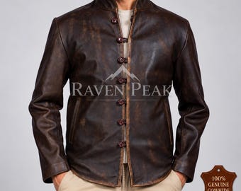 Könnte beinhalten: Eine dunkelbraune Lederjacke in Used-Optik mit Stehkragen und Knopfleiste auf der Vorderseite. Die Jacke hat lange Ärmel und zwei Seitentaschen. Der Schriftzug RAVEN PEAK ist auf der Brust zu sehen, sowie ein Etikett mit 100% GENUINE COWHIDE LEATHER.