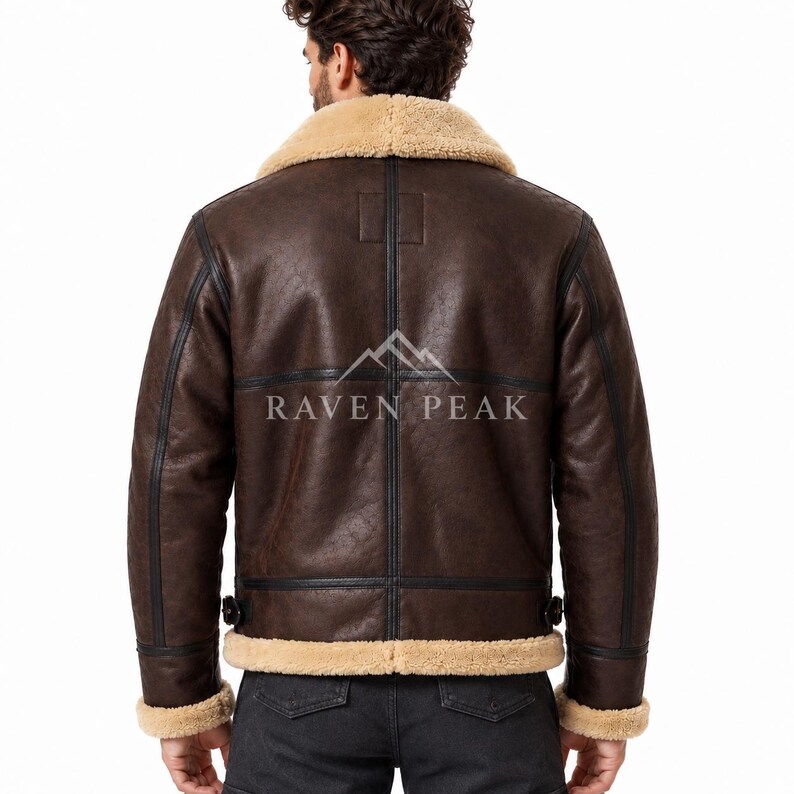 Puede incluir: Una chaqueta de cuero marr&oacute;n oscuro con cuello, pu&ntilde;os y dobladillo de borrego beige. La parte trasera presenta costuras negras, hebillas de ajuste laterales y el texto RAVEN PEAK impreso en blanco con un logo de monta&ntilde;a encima.