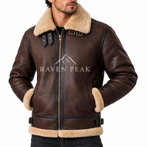 Puede incluir: Una chaqueta marr&oacute;n oscuro con cuello, pu&ntilde;os y dobladillo de borreguillo beige grueso. La chaqueta cuenta con una cremallera frontal dorada, ribetes de cuero negro y hebillas laterales ajustables. El texto RAVEN PEAK est&aacute; impreso en el pecho.