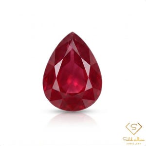 May include: A pear-shaped, faceted red gemstone with a brilliant cut, displaying deep crimson hues and sharp geometric facets. The stone is positioned above the text Saleh sallom JEWELLERY, which features a stylised letter S inside a diamond shape.