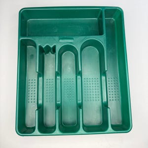 May include: A dark green plastic cutlery tray featuring one horizontal top compartment and five vertical slots of varying widths. Each vertical slot includes a textured base with a grid of small raised dots to provide grip for silverware.
