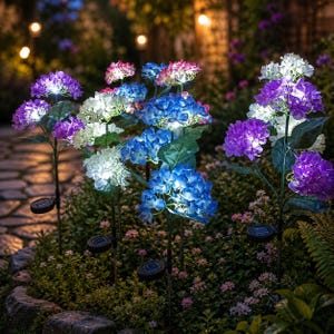 May include: A collection of solar-powered garden stakes featuring artificial hydrangea flower clusters in shades of purple, blue, and white. Each stake includes a small square solar panel at the base, with integrated LED lights illuminating the petals.