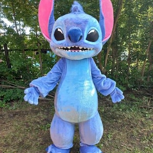 Peut inclure: Costume int&eacute;gral d'un personnage bleu extraterrestre avec de grandes oreilles et un large sourire. Le costume est principalement bleu clair avec des accents bleu fonc&eacute; et des oreilles int&eacute;rieures roses. Le personnage a de grands yeux noirs et une touffe de fourrure sur la t&ecirc;te.