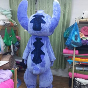 Peut inclure: Un costume int&eacute;gral bleu repr&eacute;sentant le personnage de Stitch, avec de grandes oreilles et un motif bleu fonc&eacute; distinctif dans le dos. Le costume est fait d'une mati&egrave;re douce et moelleuse. Il est con&ccedil;u pour &ecirc;tre port&eacute; par une personne.