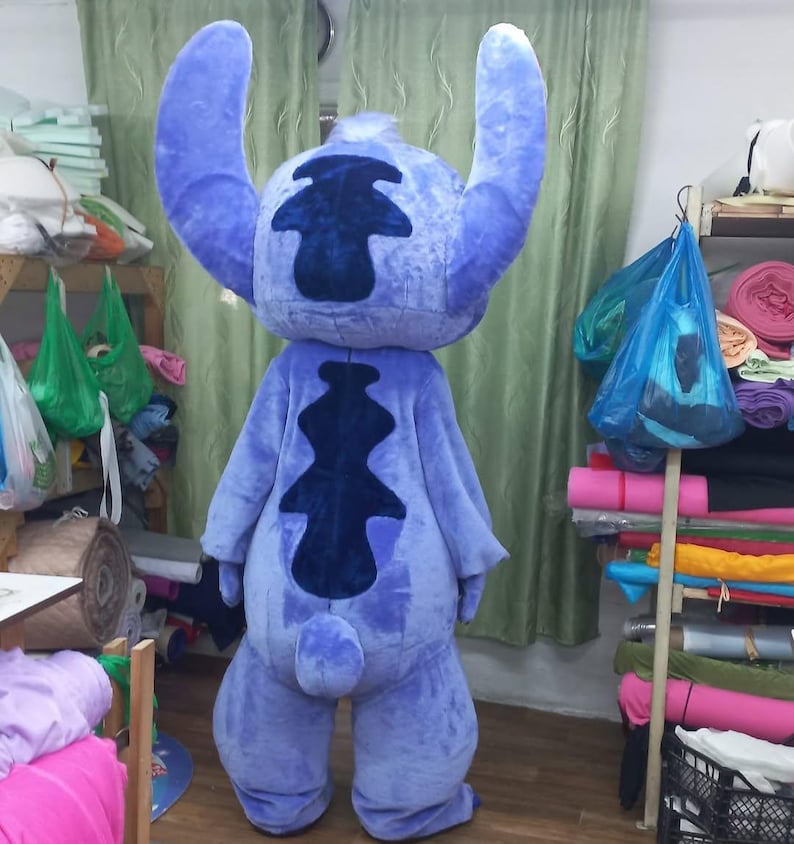 Peut inclure: Un costume int&eacute;gral bleu repr&eacute;sentant le personnage de Stitch, avec de grandes oreilles et un motif bleu fonc&eacute; distinctif dans le dos. Le costume est fait d'une mati&egrave;re douce et moelleuse. Il est con&ccedil;u pour &ecirc;tre port&eacute; par une personne.
