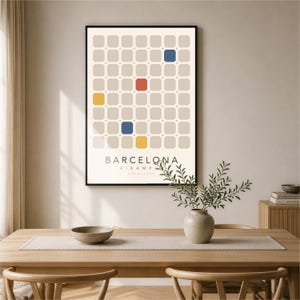 May include: A framed wall art print featuring a grid of light beige rounded squares on a cream background. Several squares are highlighted in blue, yellow, and red. The text reads BARCELONA EIXAMPLE CATALUNYA in black, sans-serif capital letters.